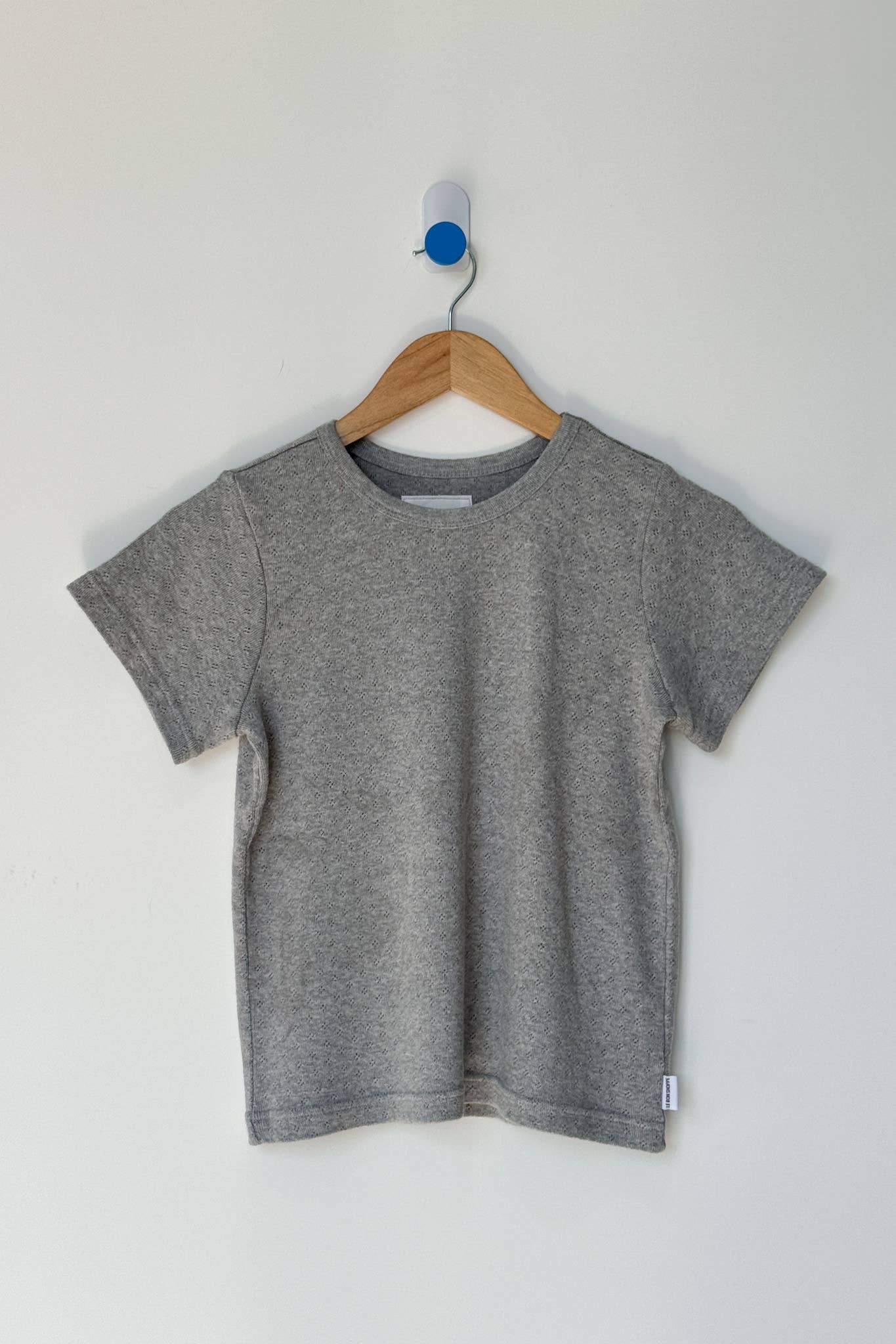 Gray t-shirt on a wooden hanger against a white background