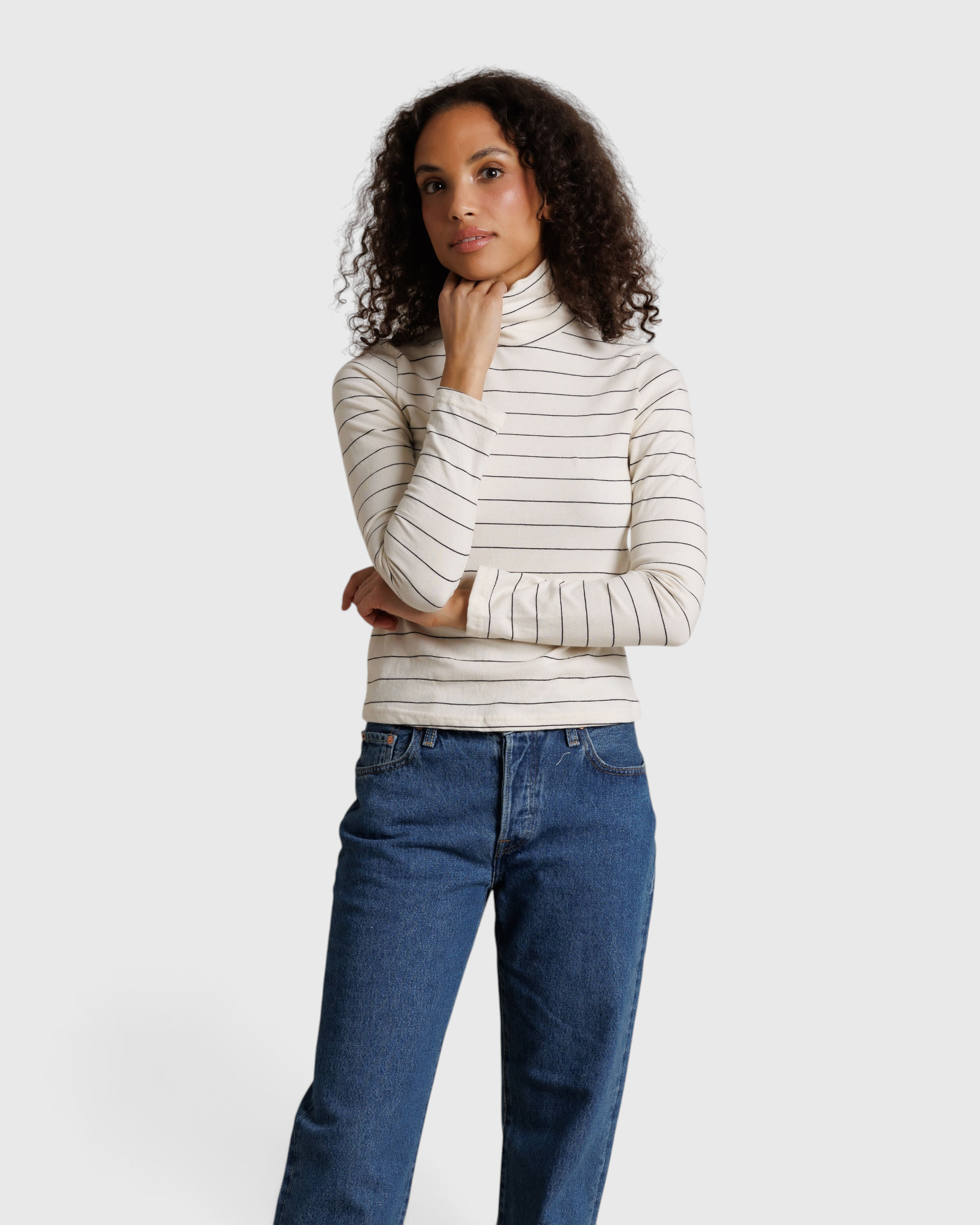 JONES + CO Cindy long sleeve turtleneck top in natural stripe worn by a model with blue jeans