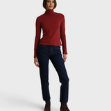 Model wearing a JONES + CO ruby red recycled cotton Cindy turtleneck paired with dark denim jeans