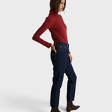 Model wearing a JONES + CO ruby red recycled cotton Cindy turtleneck paired with dark wash jeans and brown boots