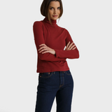 JONES + CO Cindy turtleneck in ruby red recycled cotton worn by a model with arms crossed against a neutral backdrop