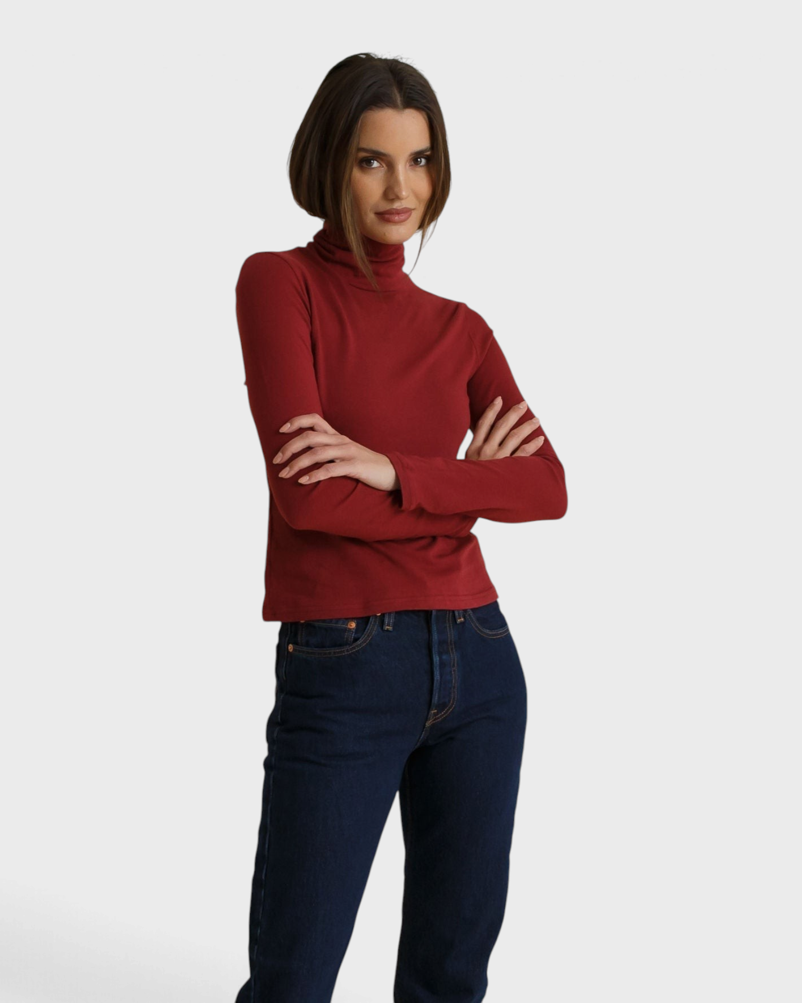 JONES + CO Cindy turtleneck in ruby red recycled cotton worn by a model with arms crossed against a neutral backdrop