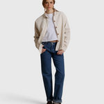 JONES + CO James button-up shirt in whitecap gray worn over a white tee and blue jeans by a woman in a studio.