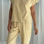 Person wearing a yellow outfit against a white curtain background