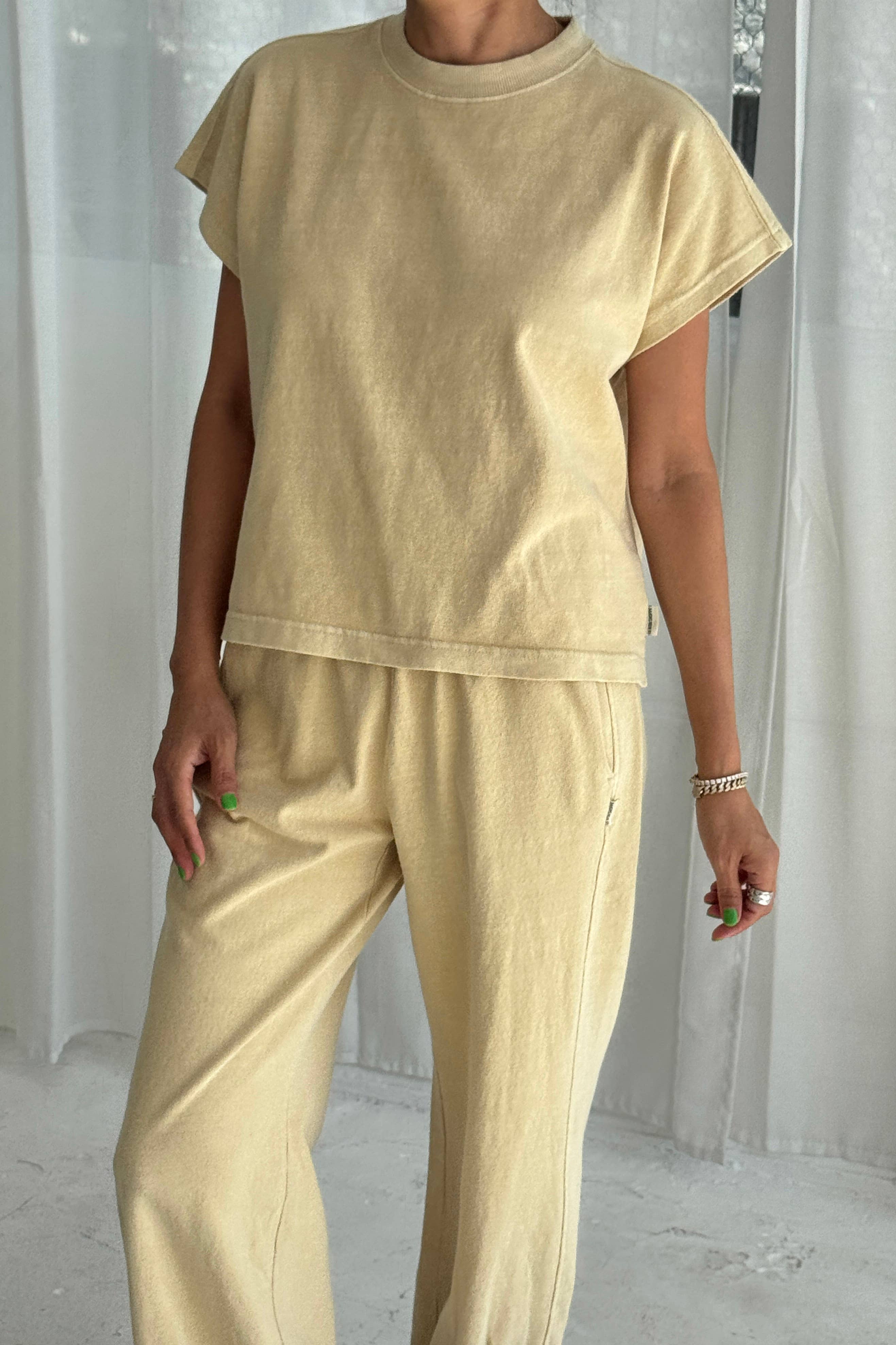 Person wearing a yellow outfit against a white curtain background