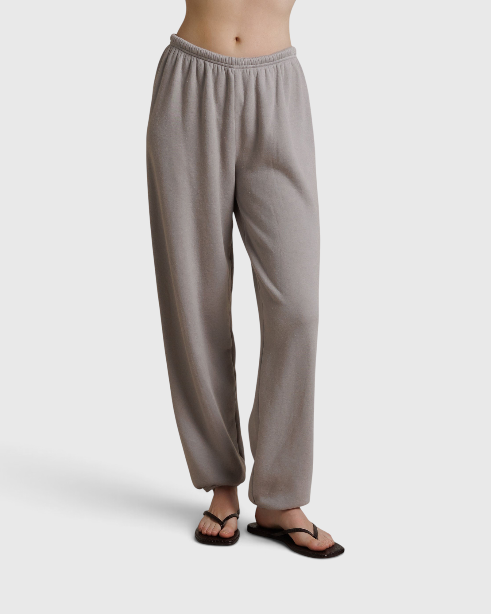 JONES + CO Dre sweatpants in cloud gray with an elastic waistband, worn with black flip-flops on a neutral background.
