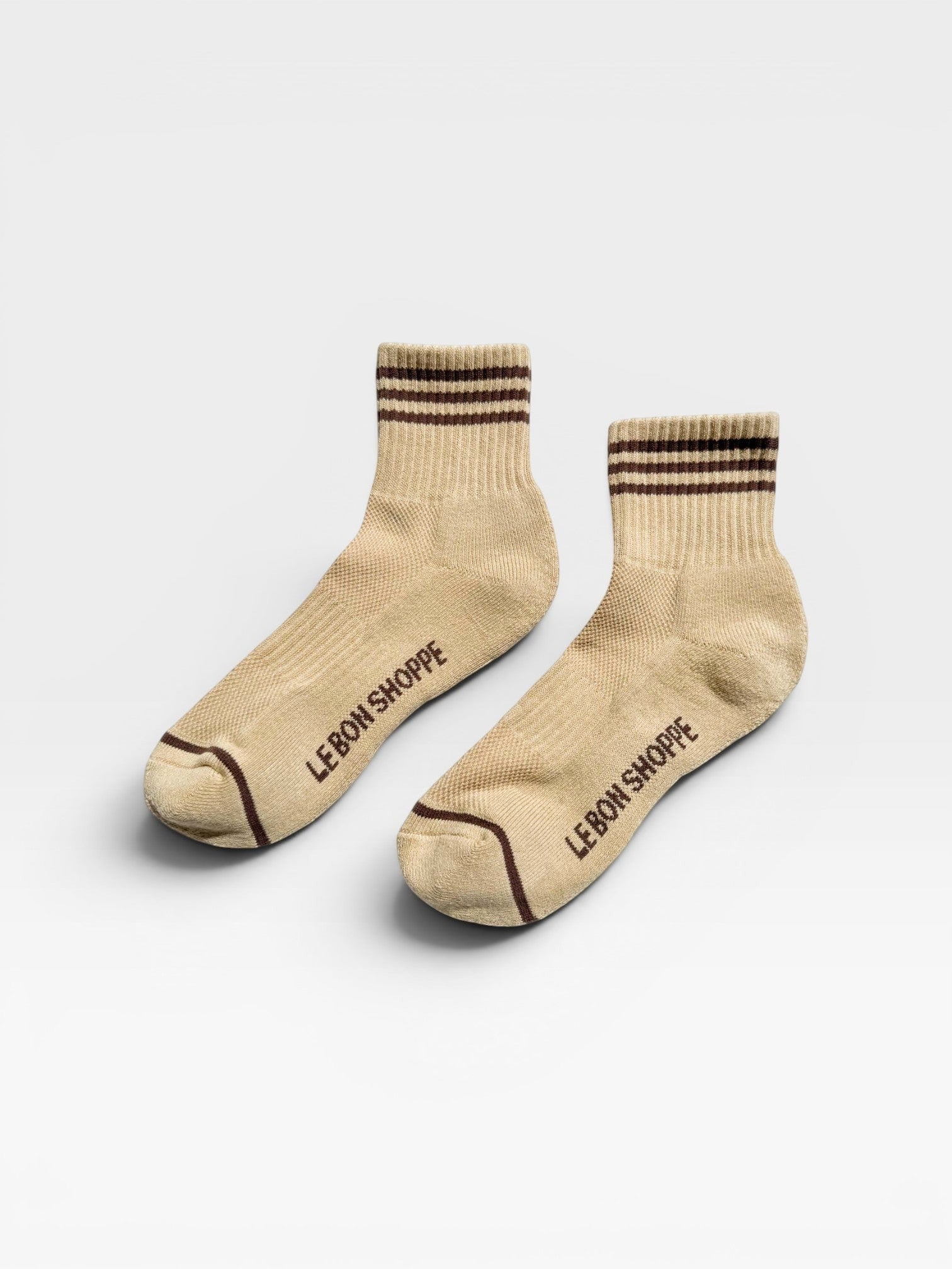 Pair of beige socks with brown stripes and 'Le Bon Shoppe' branding on a white background