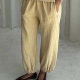 Person wearing yellow pants and a matching top on a plain background