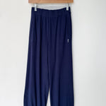 Navy blue pants hanging on a wooden hanger against a white background