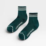 Two green socks with white stripes and 'Le Bon Shoppe' branding on a light gray background