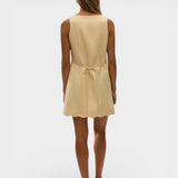 JONES + CO Alondra mini dress in daffodil yellow with a scalloped hem and tie-back detail on a model.