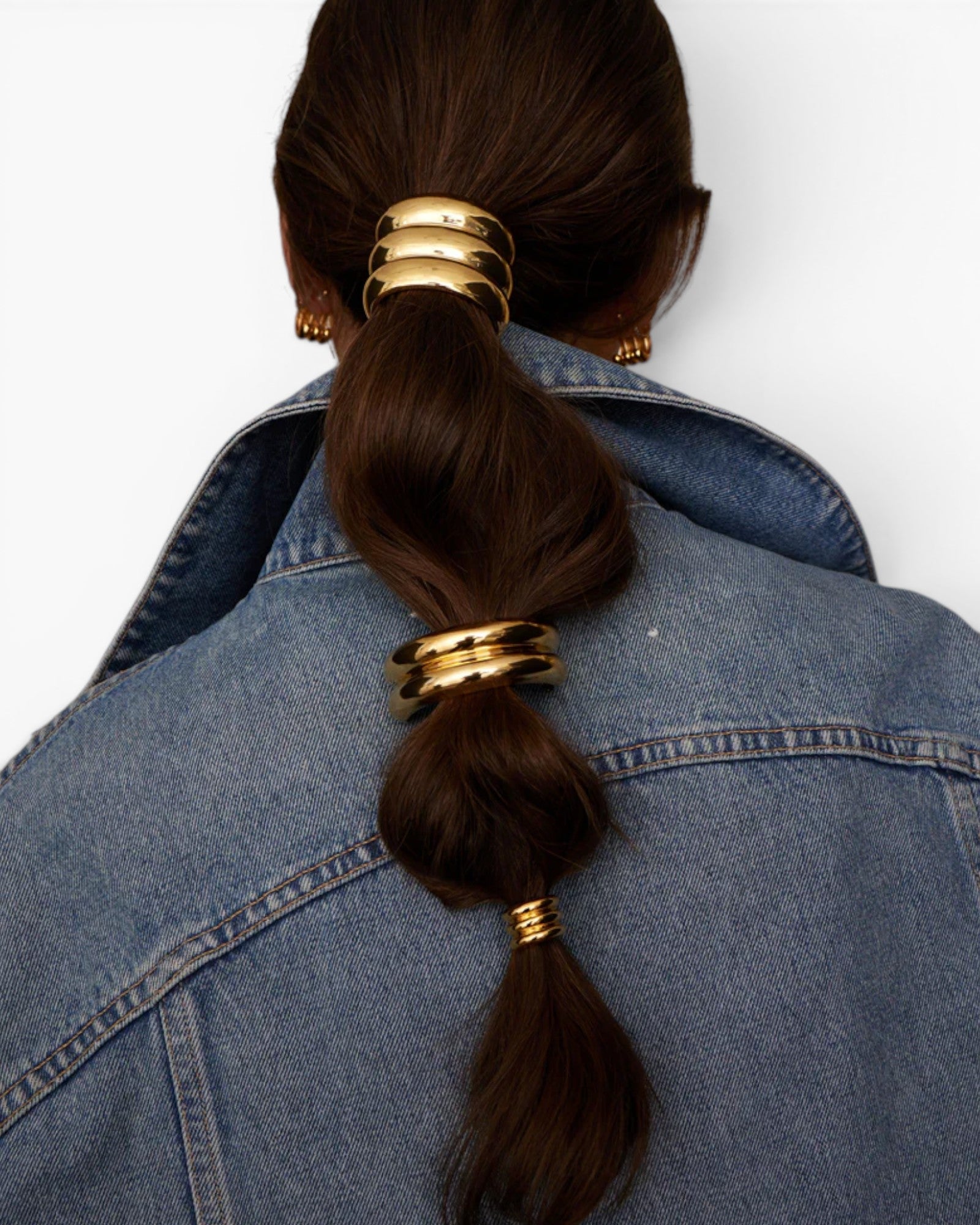 JONES + CO Anya Mini Pony Cuff in gold worn on a brunette ponytail with a denim jacket.