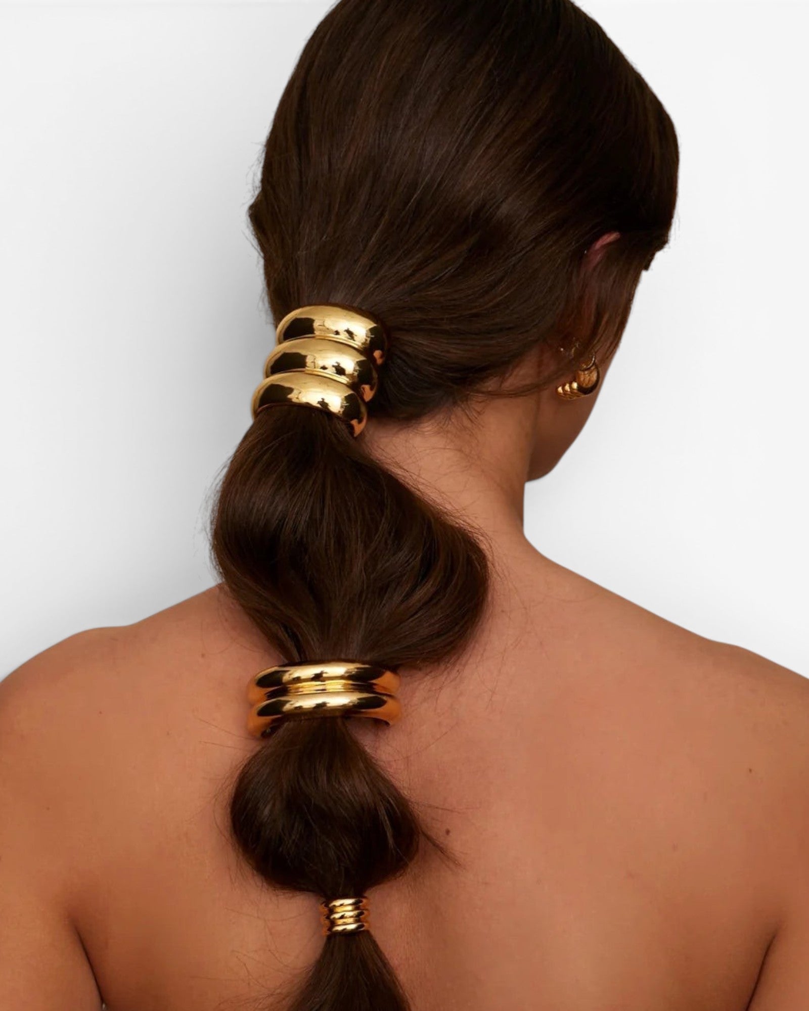 JONES + CO Anya Mini Pony Cuff in polished gold worn on a brunette ponytail to secure hair with a sleek finish.