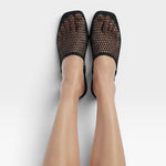 JONES + CO black mesh baboosh mules with square toe and neoprene trim worn on feet against a white background.