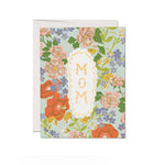 JONES + CO Blossom Serenade greeting card featuring a floral pattern with MOM text in a scalloped white frame.