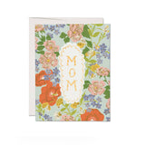 JONES + CO Blossom Serenade greeting card featuring a floral pattern with MOM text in a scalloped white frame.
