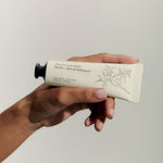 JONES + CO Maison Louis Marie No.04 Bois de Balincourt hand cream in a beige tube held by a hand.