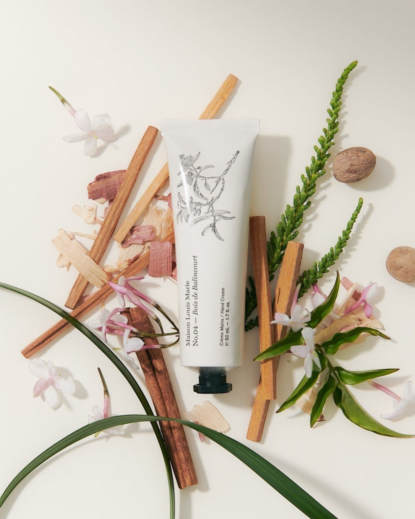 JONES + CO Maison Louis Marie No.04 Bois de Balincourt hand cream tube surrounded by botanical ingredients.