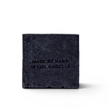 JONES + CO charcoal and lavender soap brick with Made by Hand in Los Angeles embossed on a black textured surface.
