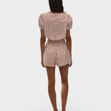 Back view of a model wearing JONES + CO Emilie playsuit in cinnamon and white gingham check with puff sleeves.