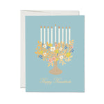 JONES + CO Floral Menorah Hanukkah card on light blue paper with illustrated flowers and candles