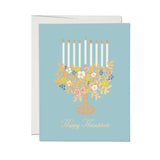 JONES + CO Floral Menorah Hanukkah card on light blue paper with illustrated flowers and candles