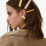 Model wearing JONES + CO gold domed Glossy Bar Barrette with a crystal-encrusted barrette in her brown hair.