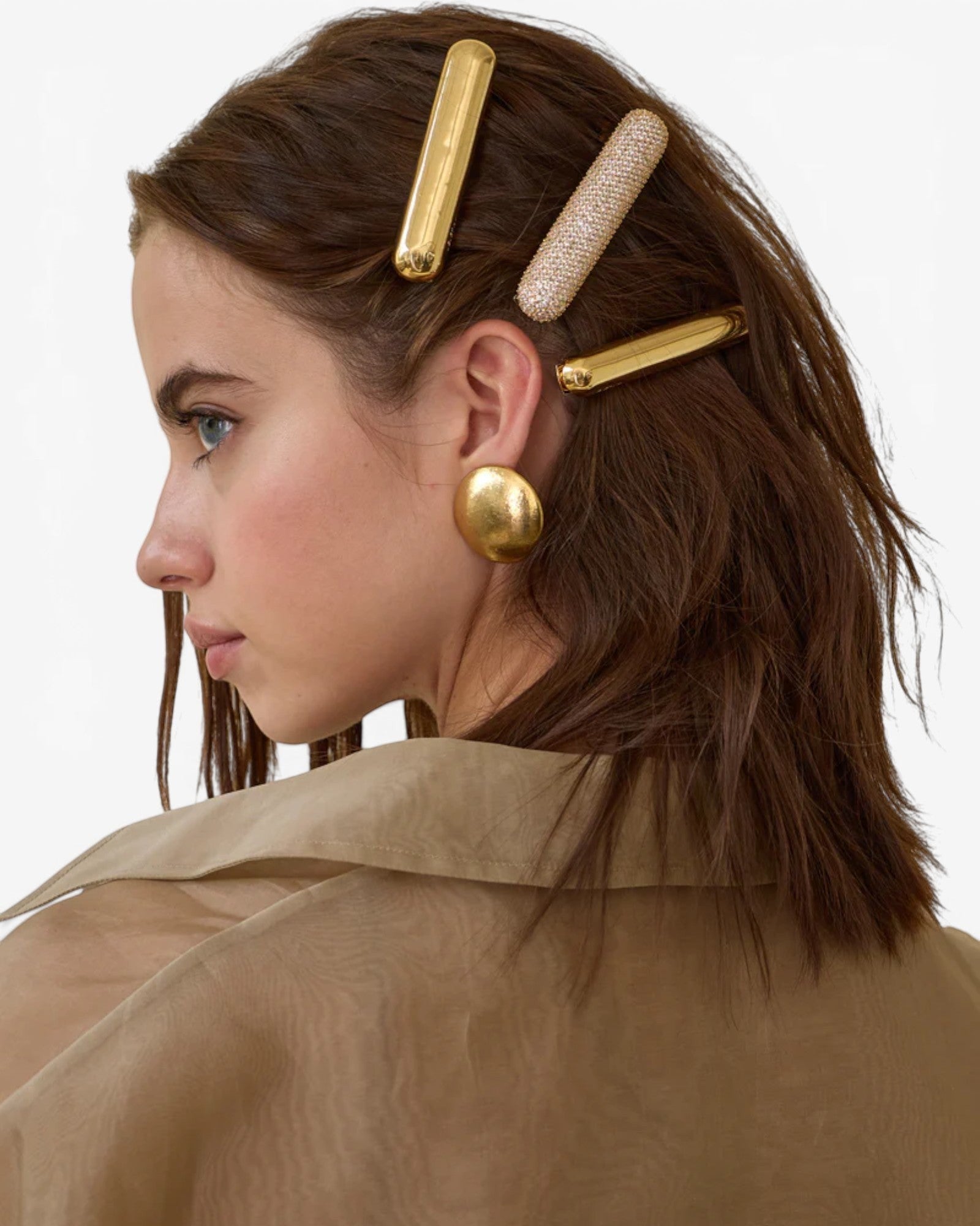 Model wearing JONES + CO gold domed Glossy Bar Barrette with a crystal-encrusted barrette in her brown hair.
