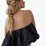 Model wearing JONES + CO gold Glossy Bar Barrette in a styled ponytail with a black strapless top.