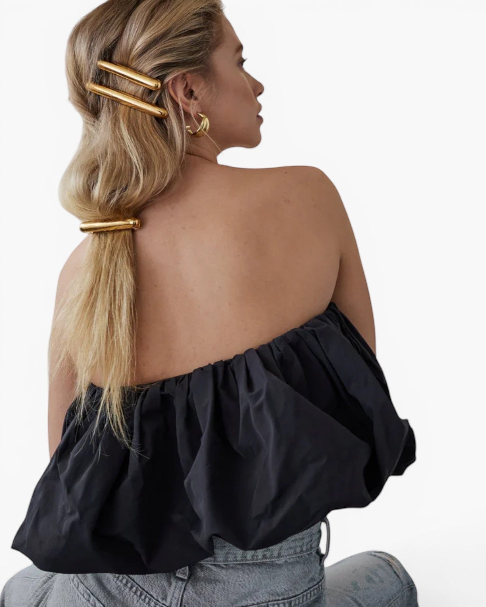 Model wearing JONES + CO gold Glossy Bar Barrette in a styled ponytail with a black strapless top.