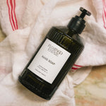 JONES + CO Heirloom Tomato hand soap in a dark green fluted glass bottle with a pump dispenser on a linen cloth.