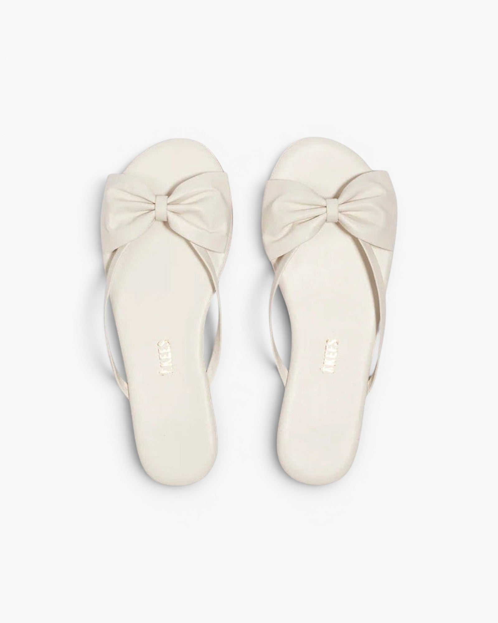 JONES + CO Lily cream leather flip flop sandals featuring an oversized bow detail and cushioned insole.