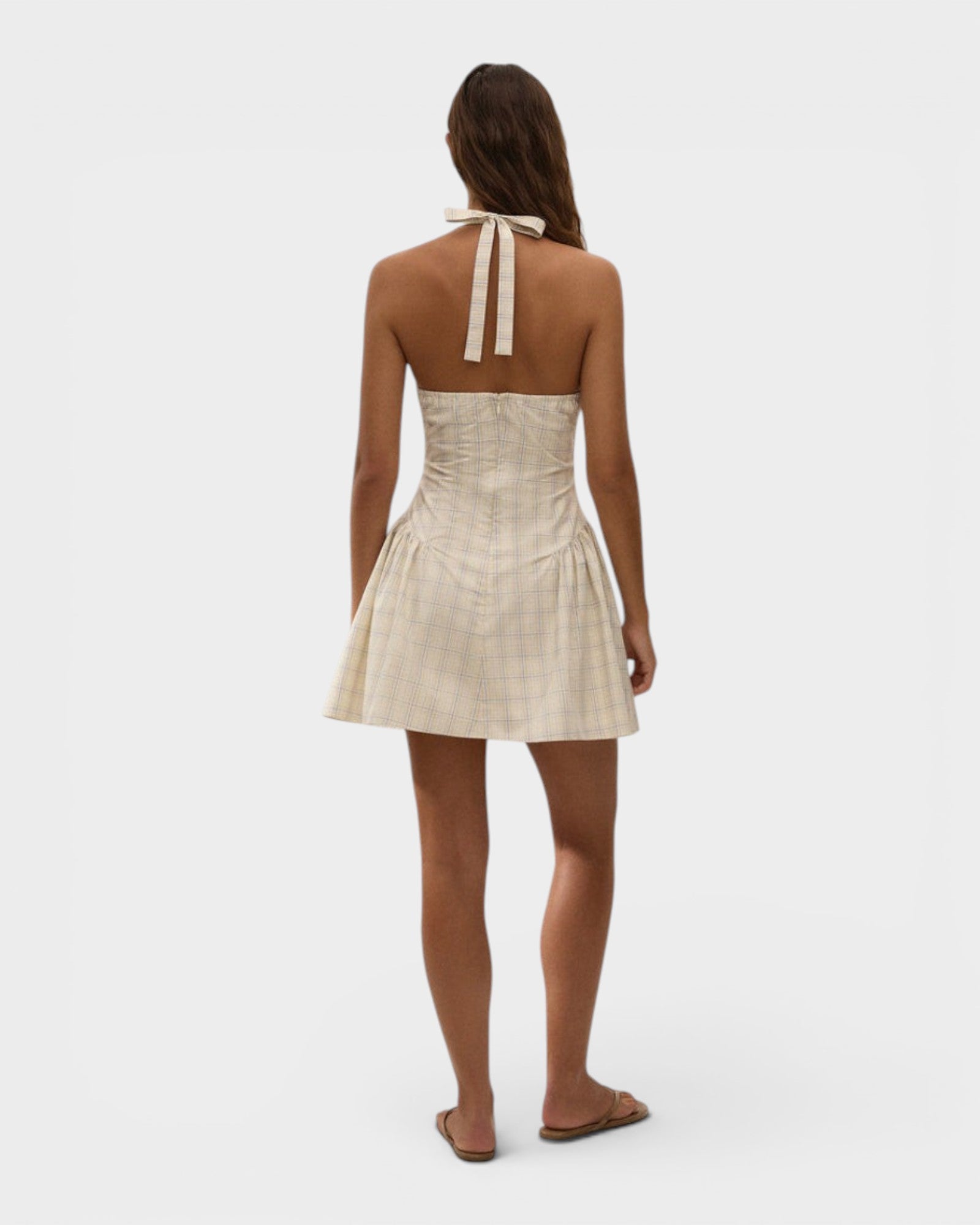 Model wearing JONES + CO Lola mini dress in antique white with a plaid check pattern and halter neck tie back.