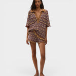 Model wearing JONES + CO Ramona Stripe Luis shorts and matching chevron knit polo shirt in purple and yellow tones.