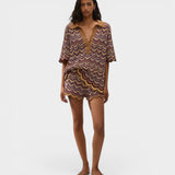Model wearing JONES + CO Ramona Stripe Luis shorts and matching chevron knit polo shirt in purple and yellow tones.