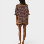 Model wearing JONES + CO Luis Short in Ramona Stripe, a multi-colored chevron knit set with scalloped hem edges.