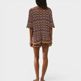 Model wearing JONES + CO Luis Short in Ramona Stripe, a multi-colored chevron knit set with scalloped hem edges.