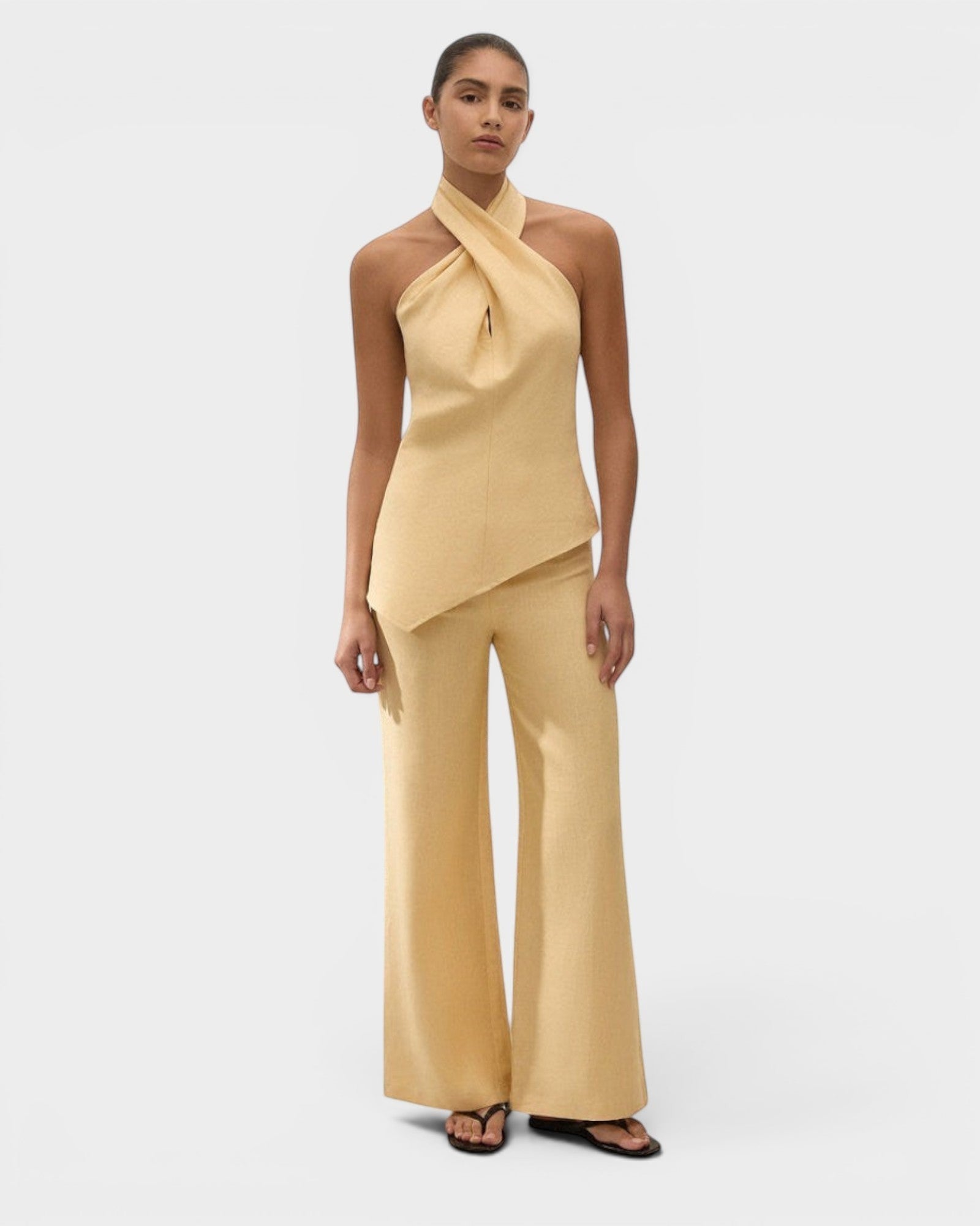 JONES + CO Maria Top in daffodil yellow linen with a halter neck and asymmetrical hem worn by a model.