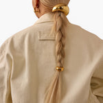 JONES + CO gold mini dome pony cuff hair accessory worn on a blonde braid with a matching glossy dome hair tie.