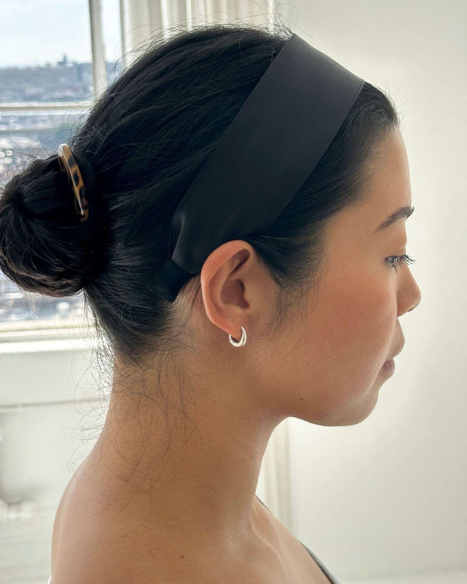 Model wearing a sleek black JONES + CO Olivia Headband in ebony with a comfortable fabric finish.