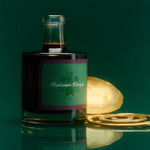 JONES + CO organic balsamic vinegar in a glass bottle with a green label, set against a dark green reflective surface.