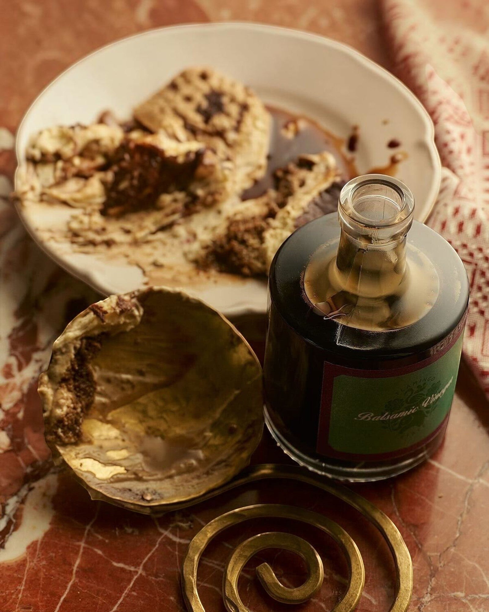 JONES + CO organic balsamic vinegar in a glass bottle, aged in oak barrels, served with gourmet food on marble.