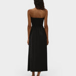 JONES + CO Orla black strapless midi dress in stretch-cotton with a smocked bodice, worn by a model against a wall.