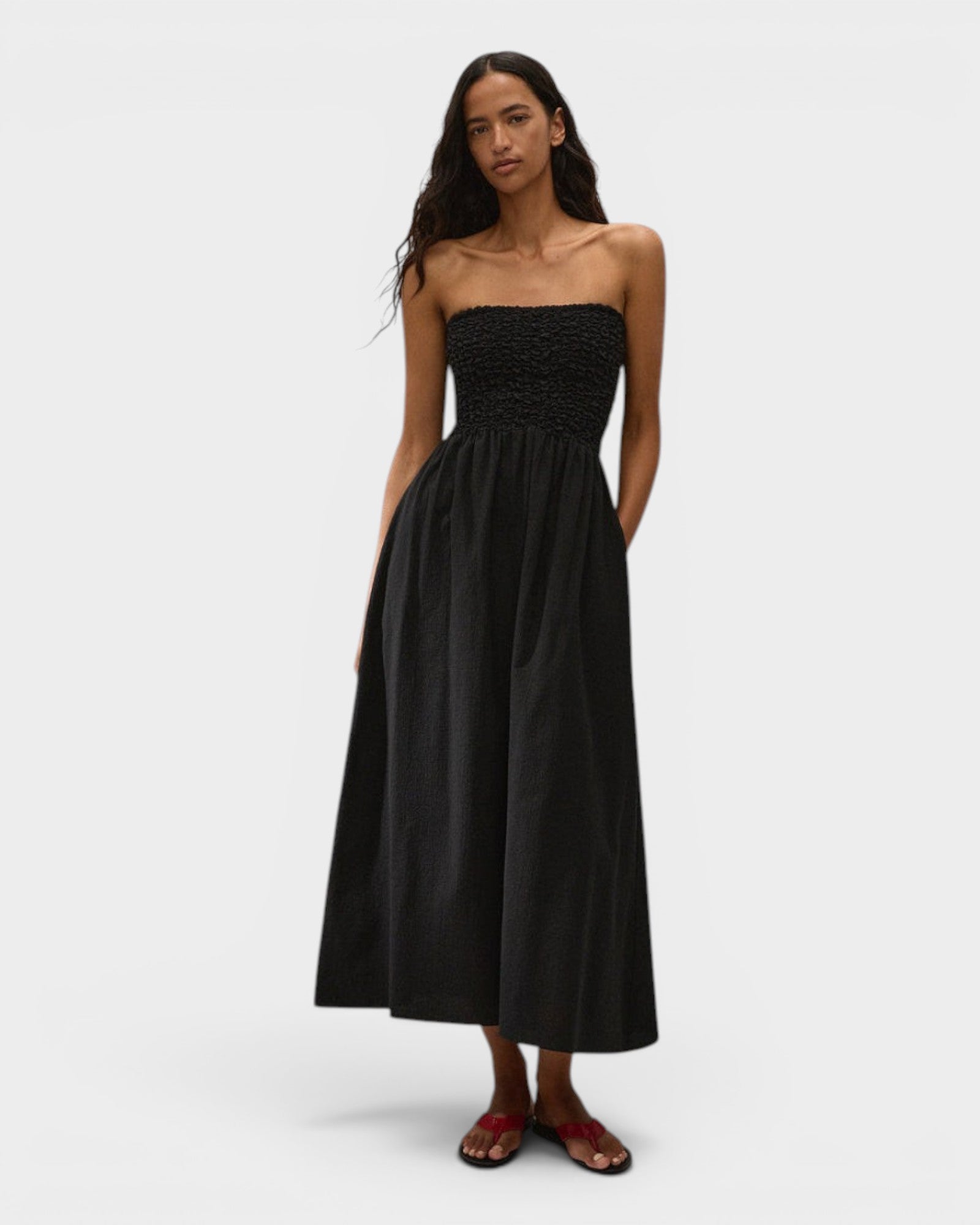 Model wearing JONES + CO black strapless midi dress in stretch-cotton with a smocked bodice and side pockets.