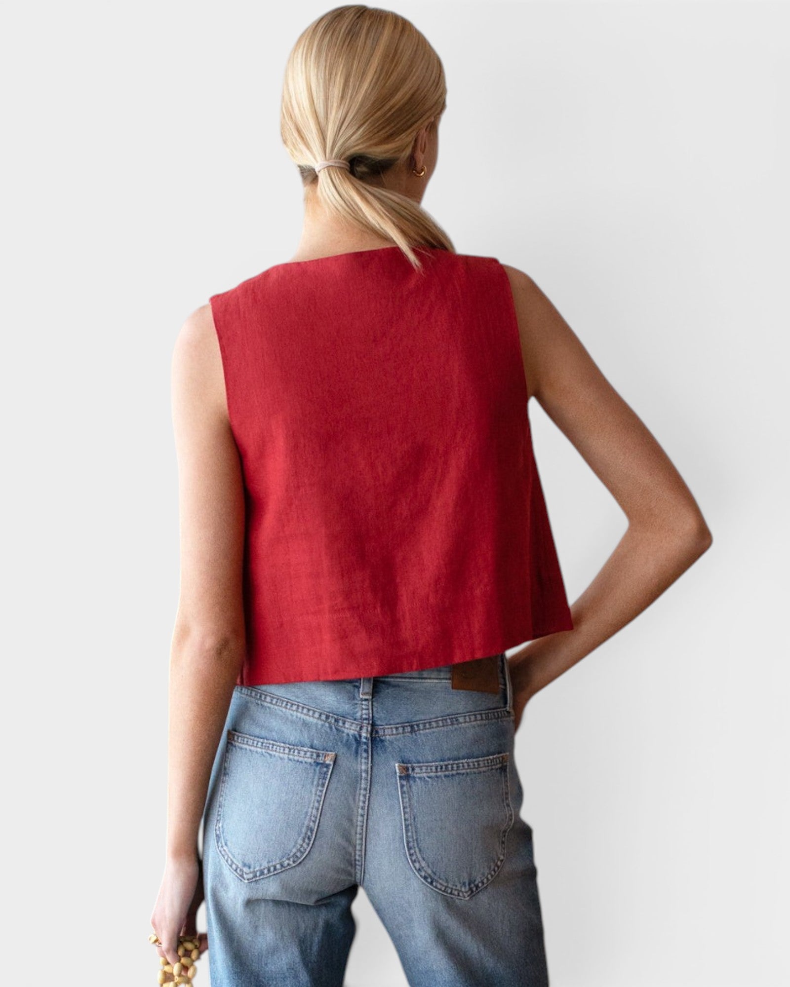 JONES + CO sleeveless linen top in pompeian red with a boxy silhouette, worn by a model with blue jeans.