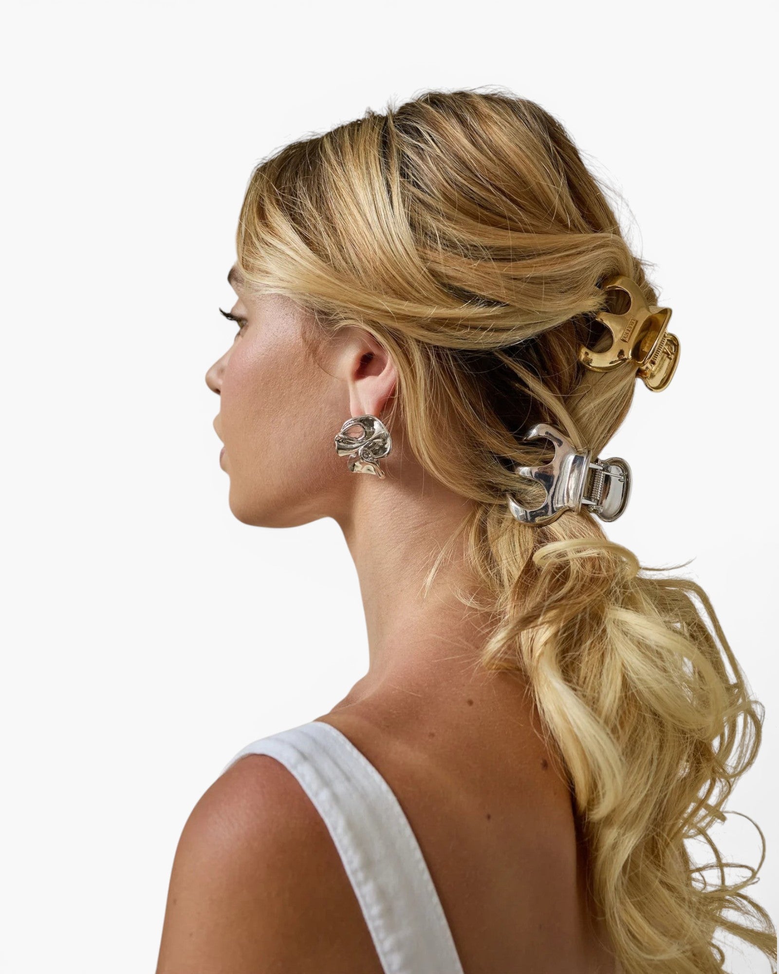Model wearing JONES + CO Selene stainless steel claw clips in gold and silver with a modern curved design.