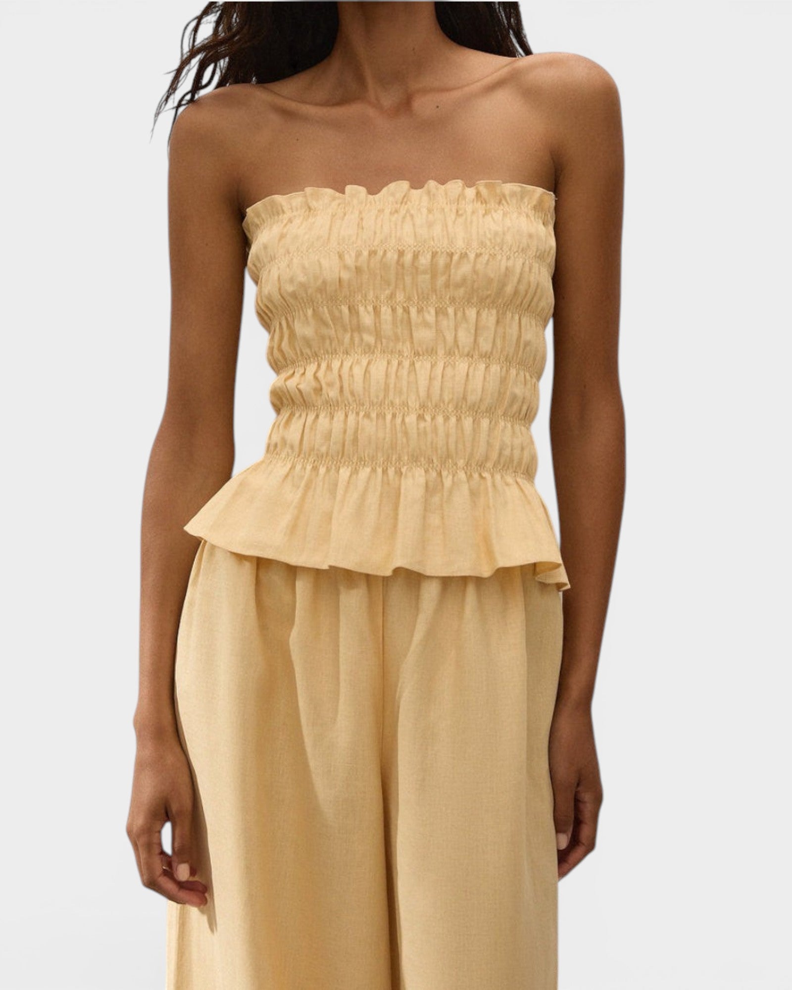 JONES + CO Tiera strapless linen top in daffodil yellow with shirred bodice, frill neckline, and peplum hem.