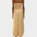 Model wearing JONES + CO daffodil yellow strapless linen top with shirred bodice and peplum hem from behind.