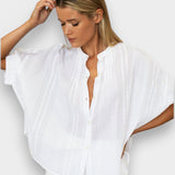 Model wearing a white JONES + CO organic cotton seersucker mandarin collar top with dolman sleeves.