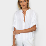 Model wearing a white JONES + CO organic cotton seersucker top with a mandarin collar and dolman half sleeves.